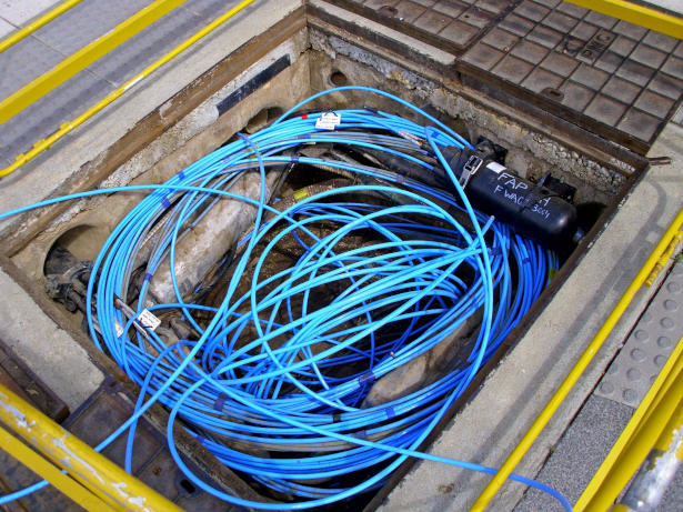 Coiled fiber optic cable with blue casing set in an underground pit